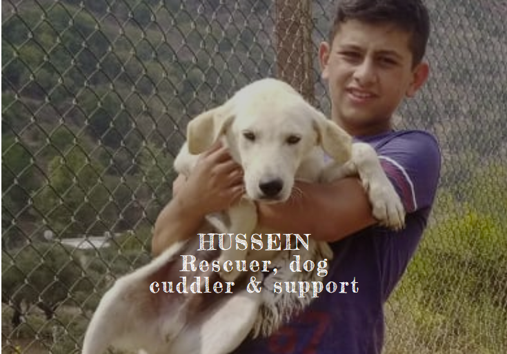 Hussein, rescuer and dog cuddler, holding a white puppy